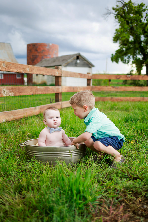 baby boy sitting in a large tin can with his big brother next to him