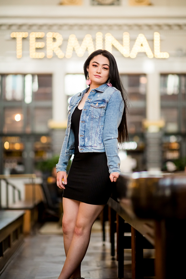 A girl in a black dress and jean jacket posing in front of 'The Terminal' sign at Union Station